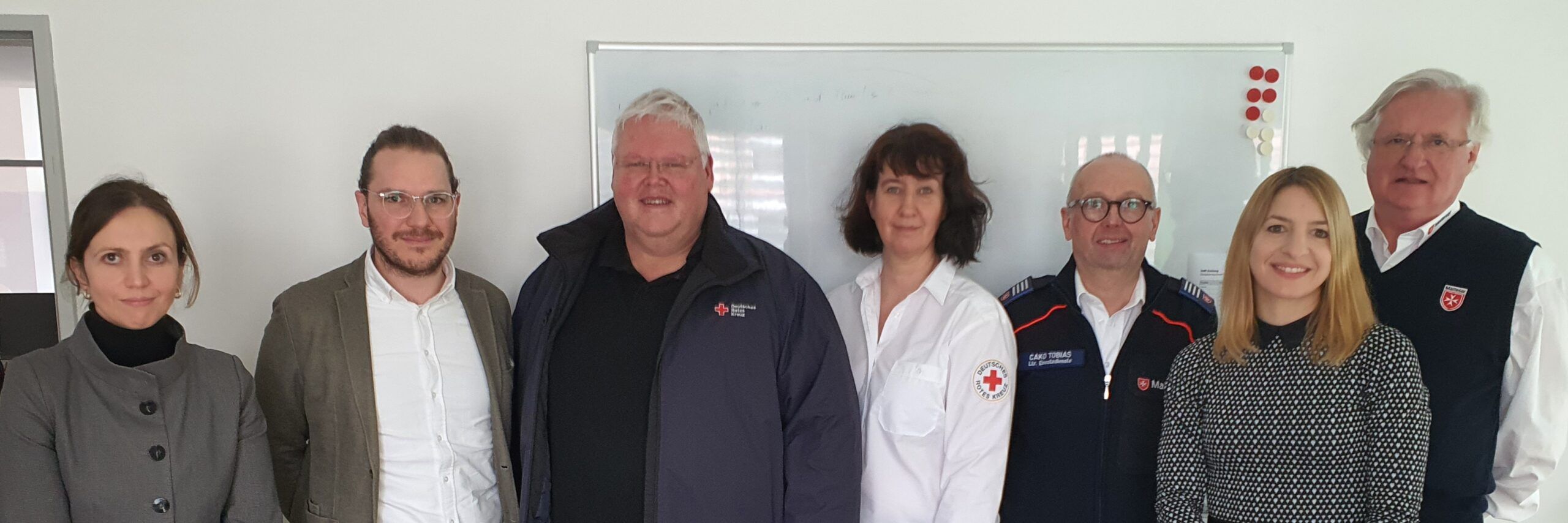 Eine Gruppe von Menschen steht zusammen vor einem Whiteboard